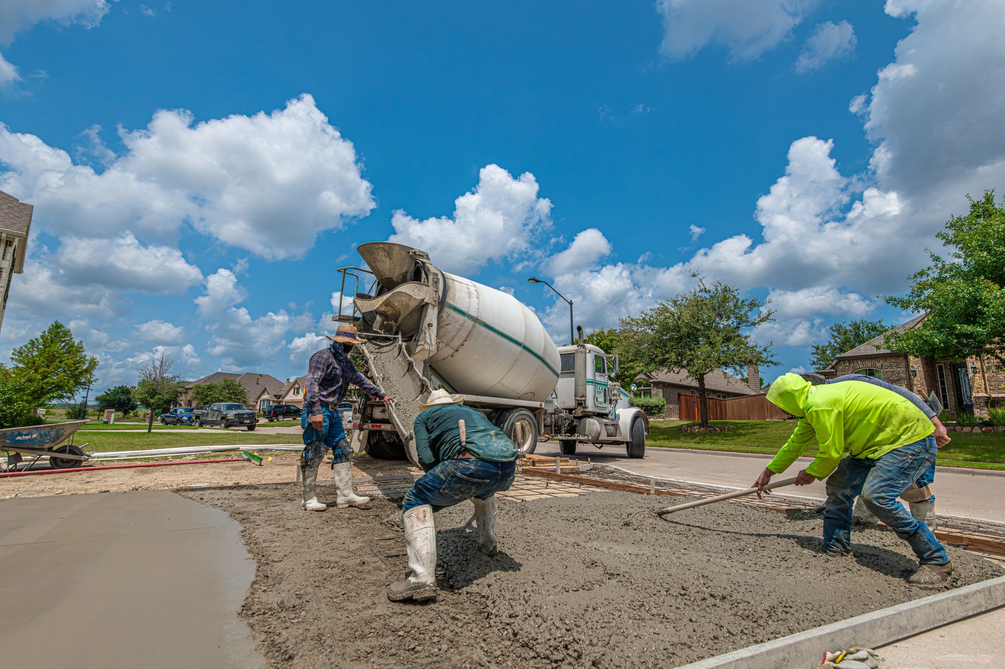 Tampa Bay concrete crew pouring and hand-finishing a residential driveway, cement mixer truck on site